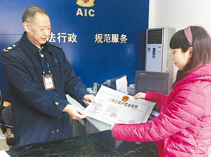 肖坤兰(右一)从周福平手里接过年检后的营业执照